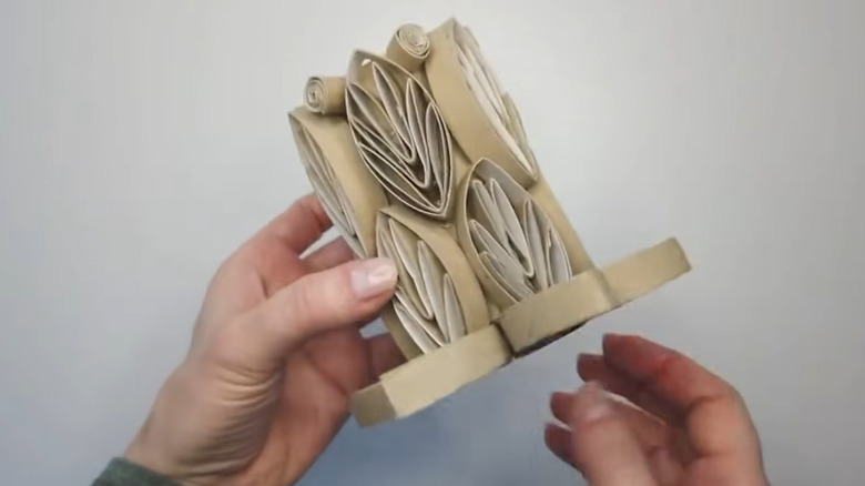 Person holding a countertop organizer made from a toilet paper tube with toilet paper tube decorations