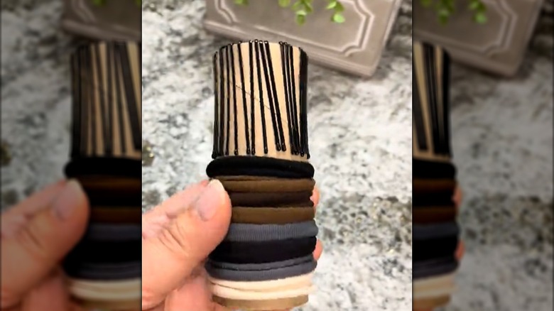 Toilet paper tube being used to hold bobby pins and ponytail holders