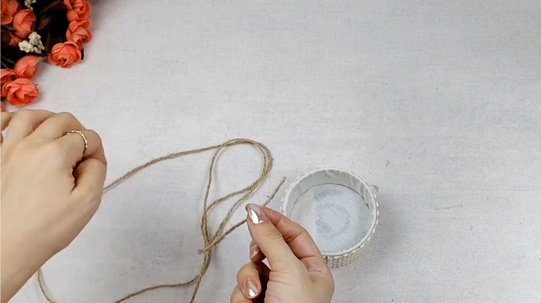 A woman transforms a tuna can with twine