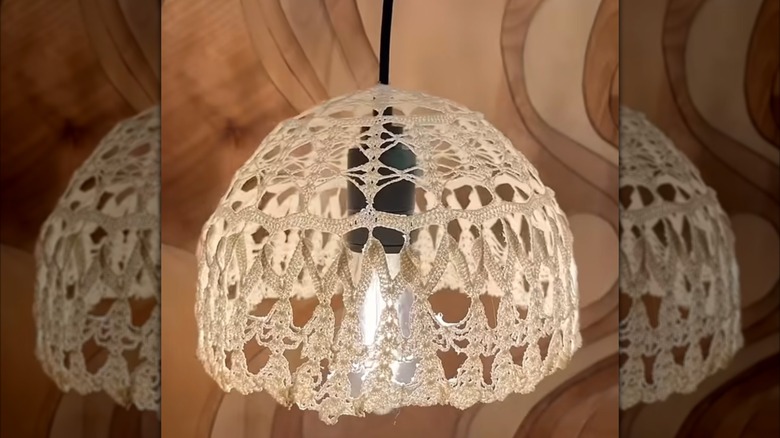 A black corded pendant light fixture has a DIY boho lampshade made from a vintage doily