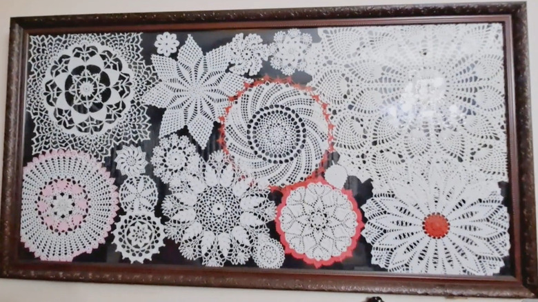 Assorted thrifted lace doilies behind glass picture frame on wall