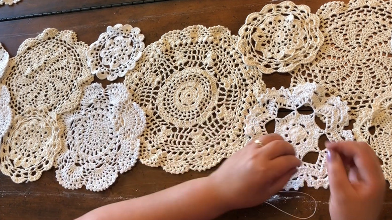 Woman sewing vintage lace doilies together as traditional-style table runner