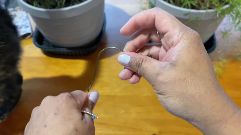 Hands bending a wire clothes hanger