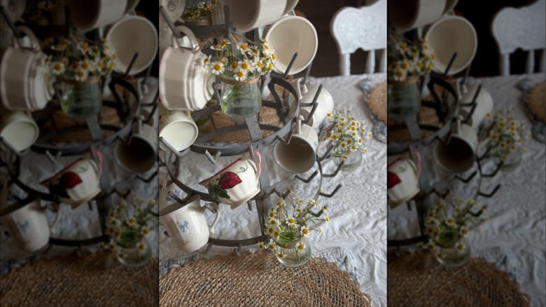 A circular mug rack with yogurt jars full of flowers hanging from it