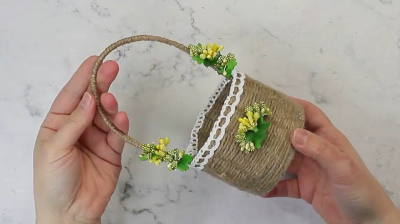 A basket made from a togurt container decorated with yellow flowers