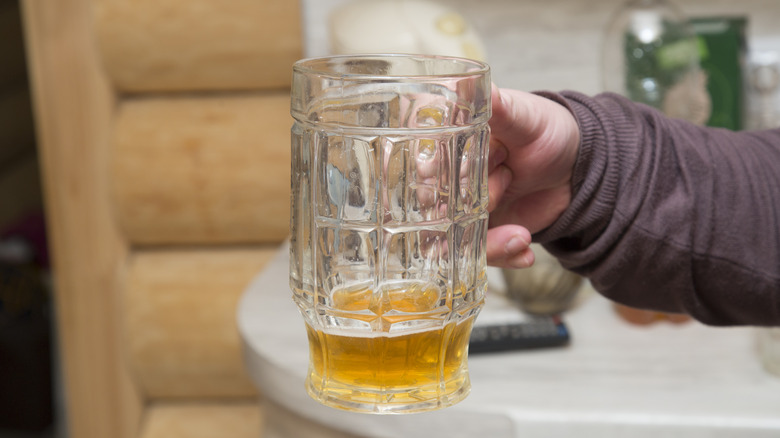 Hand dumping stale beer down the drain