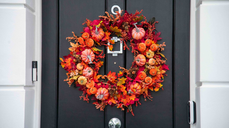 A black front door with an orange and red fall wreath.