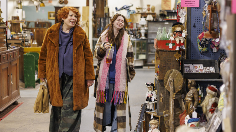 Two women smiling while browsing a thrift store