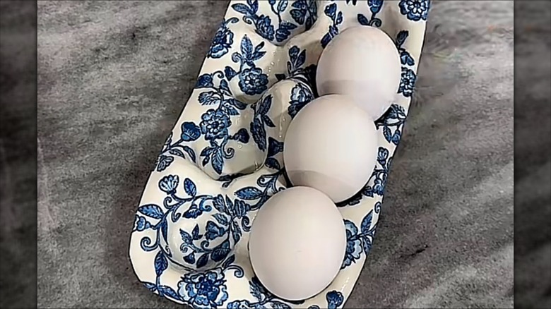 An egg holder made out of clay with a blue vintage design