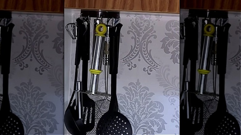 Utensils hanging from the underside of a floating cabinet