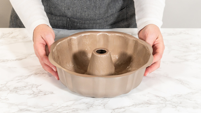 Female hands around a Bundt pan placed on a marble counter