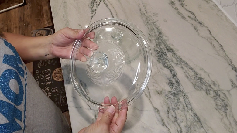 hands holding glass Pyrex lid