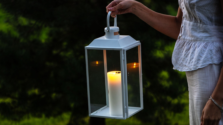 Woman holding lantern with lit candle inside