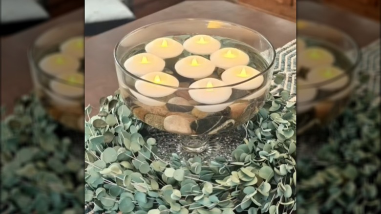 Cake plate display filled with stones, water, and floating candles