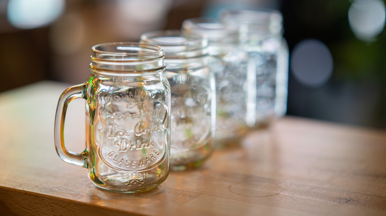 empty mason jars lined up on wood surface