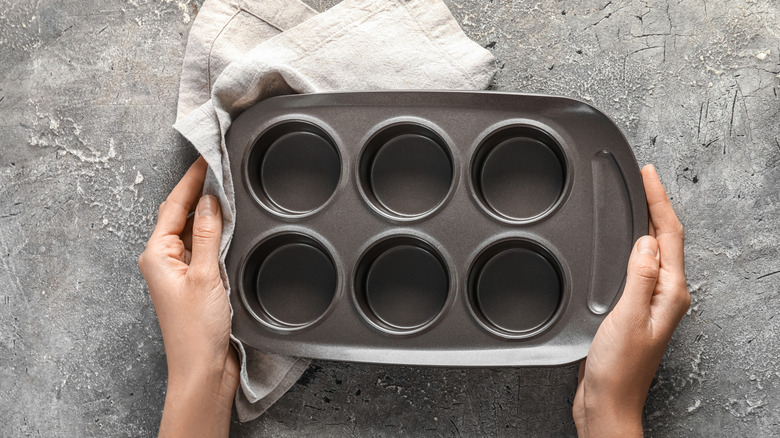 Someone holding a blank muffin tin