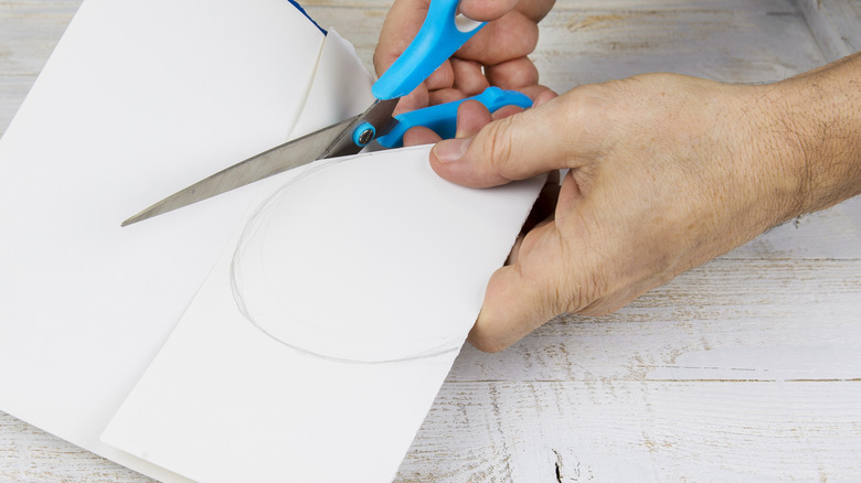 Hands cutting a circle out of paper