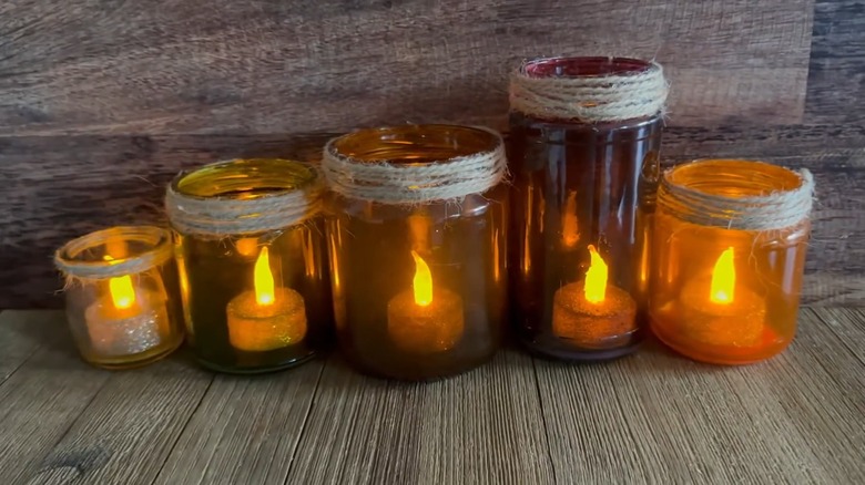 Tealights inside tinted glass jars with twine around their necks
