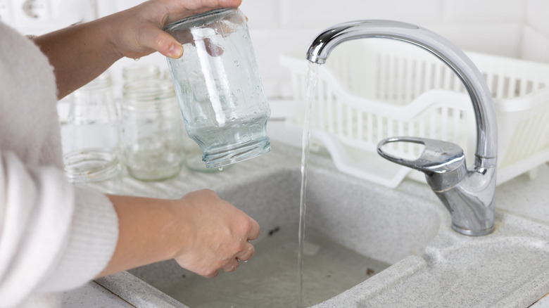 Female hands washing a glass jar in a kitchen sink