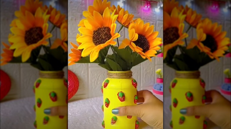 Hand holding a yellow-painted jar with 3D strawberry detail
