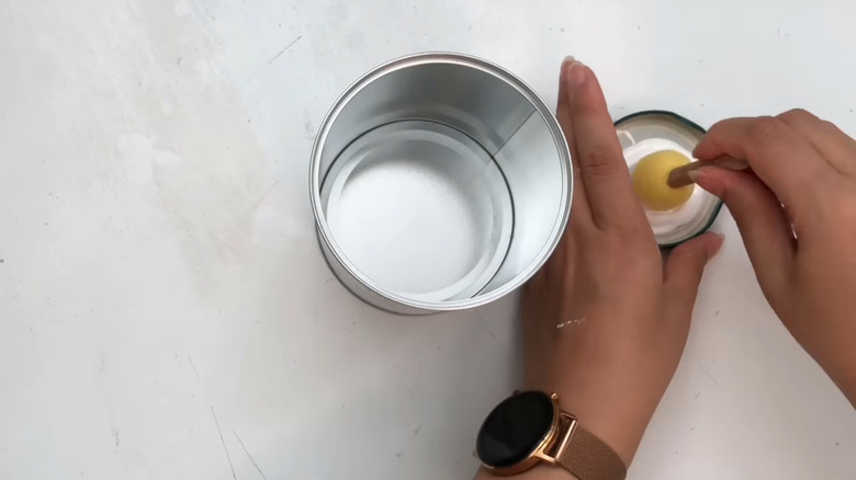 A woman prepares to paint an empty tin can