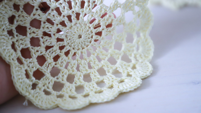 Person holding a small white doily