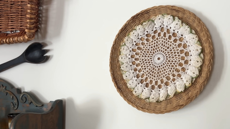 DIY wall decor made from wicker backing and a vintage doily hanging on a wall near other decor