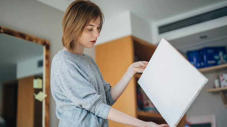 A woman looks at a plain white canvas