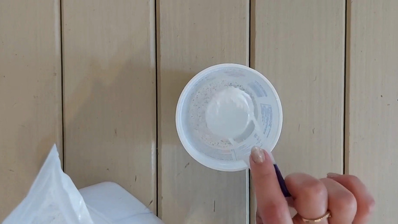 A person mixing plaster of paris in a plastic container
