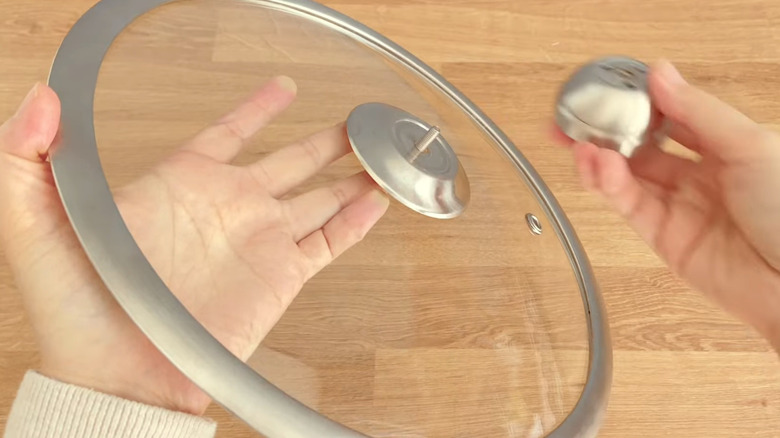 A person removes the handle from a pot lid