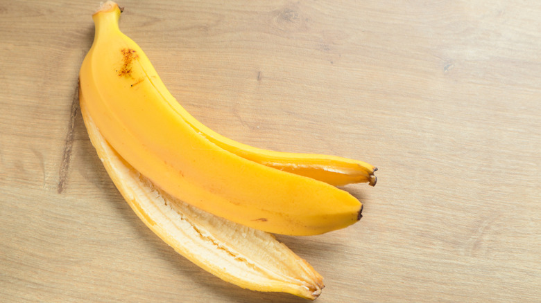 A yellow banana peel sitting on a wood surface