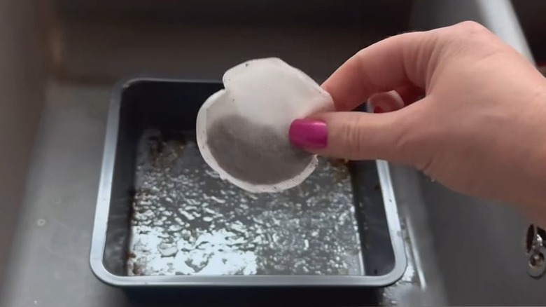 Woman holding tea bag to clean dirty cookware