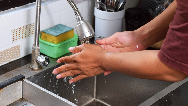 Person washing hands in kitchen sink