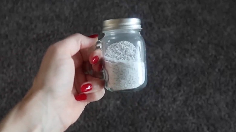 Woman with tea and baking soda shaker to clean carpet