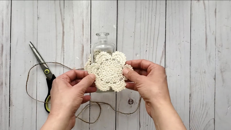 hands holding doily over vase