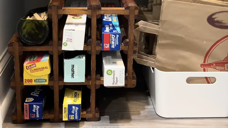 thrifted wine rack with square openings used to store foil, parchment paper, and plastic wrap in a pantry