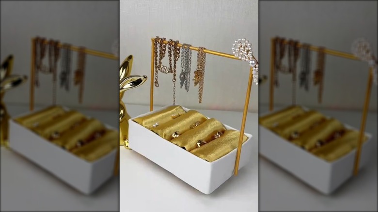 DIY jewelry holder made from a cardboard box, toilet paper tubes, and dowels