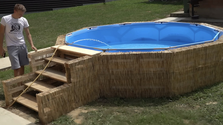 A man making a DIY pool frame out of pallets for an above ground pool