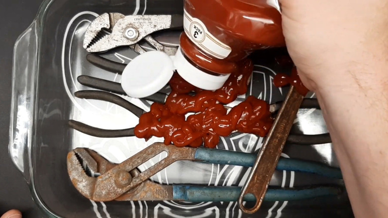 Close-up of a ketchup bottle pouring ketchup onto garden tools