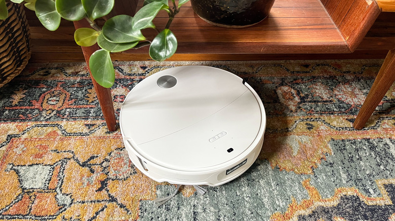 Roborock Qrevo Edge 3 Pro robot vacuum on an area rug coming out from under a table