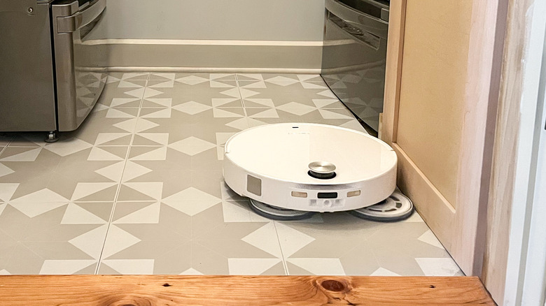 Roborock Qrevo Edge 3 Pro robot vacuum and mop mopping right against the edge of a cabinet door with its mop pad arm