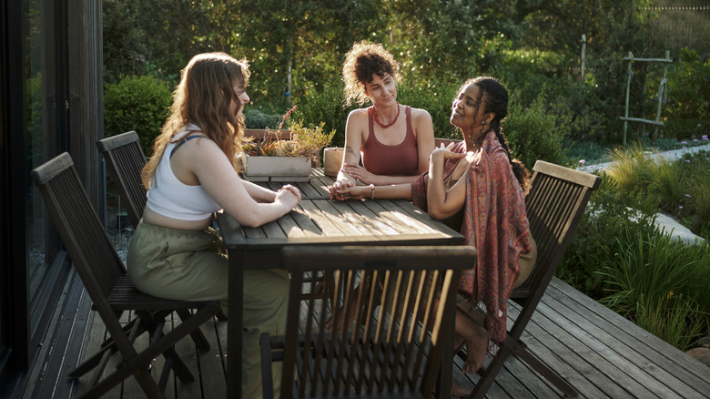 Three women chatting on the patio in a backyard