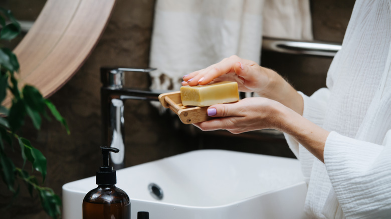 A woman holds a soap dish in a modern bathroom