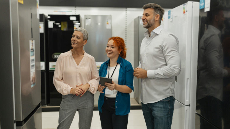 customers shop for refrigerators, consulting a salesperson for help