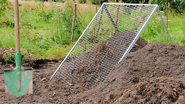 A shovel, a screen , and a pile of sifted soil