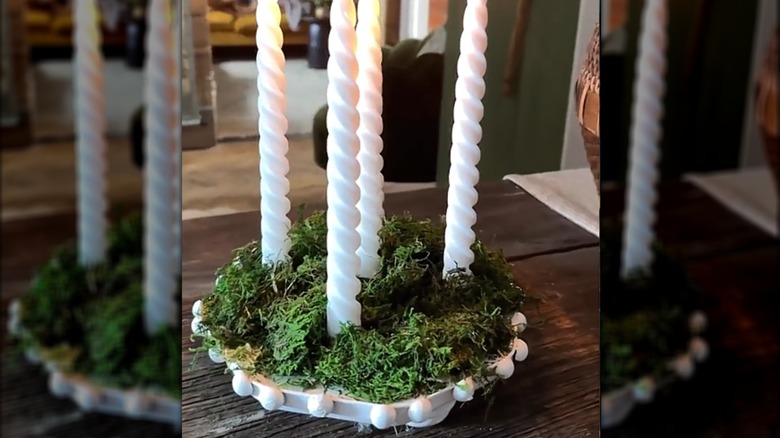 Candle holder made from a cookie tin lid with faux moss in the bottom