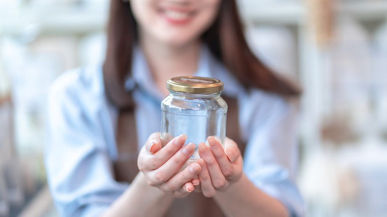 A woman holding an empty pickle jar.