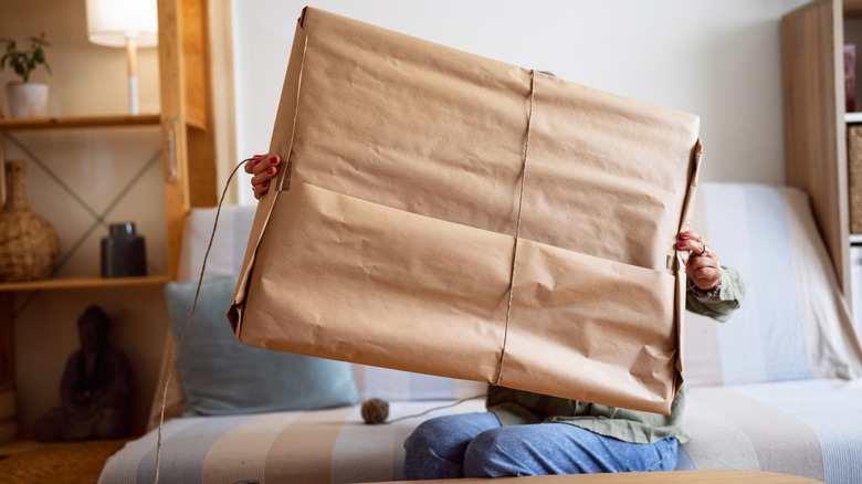 Woman opening giant package with brown paper