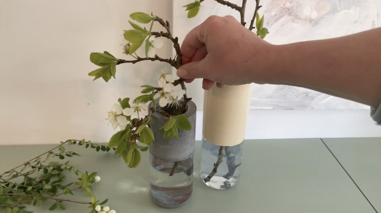 hand putting flower in DIY glass and cement vase