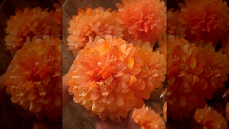 A person holds up marigolds made with coffee filters